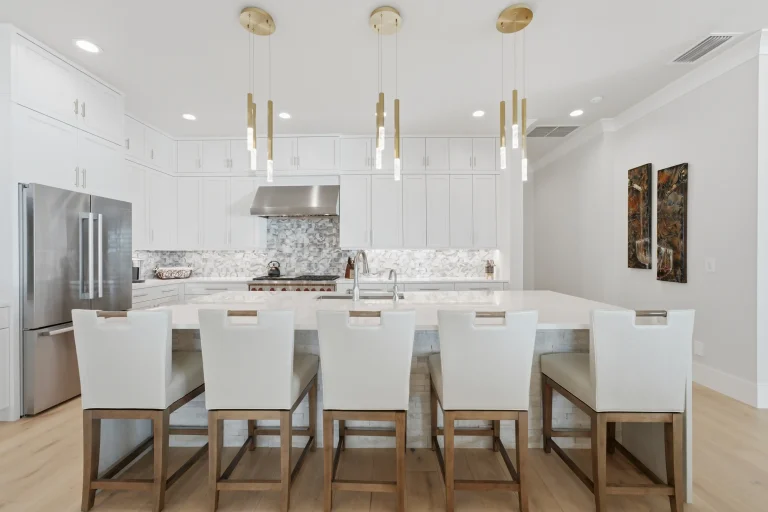 White kitchen with long island and pendant lights