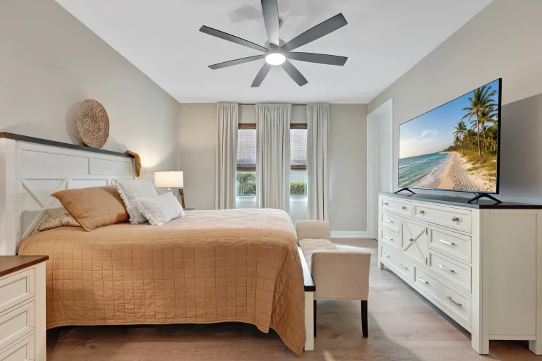 Coastal bedroom with ceiling fan and beach art