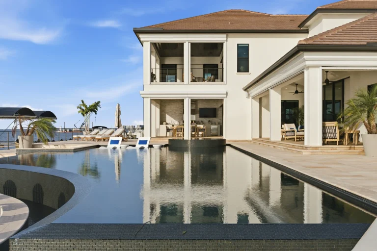 Waterfront home with pool reflecting the house